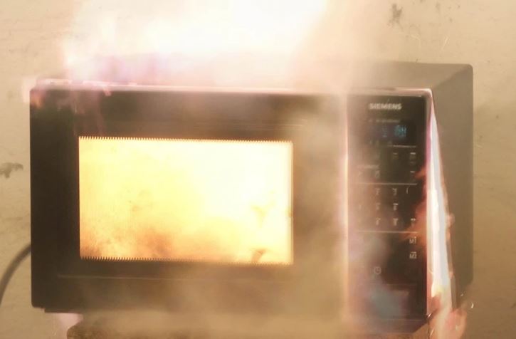 Mikrovlnná rúra v plameňoch, problematické bezpečnostné riziko v kuchyni.