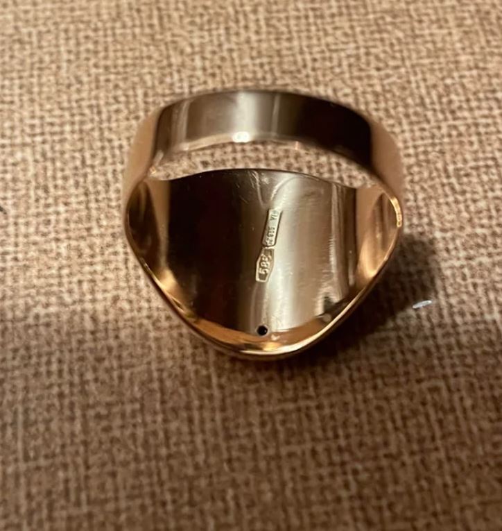 Zlatý prsteň s pečaťou na hnedom plátne, detail vnútornej značky.