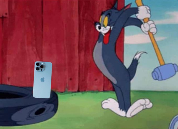 Kocúr drží kladivo a mieri na pneumatiky s iPhone.