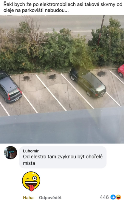 Parkovisko s autami a olejovými škvrnami, komentár o elektromobiloch hovorí o ohořelých miestach.