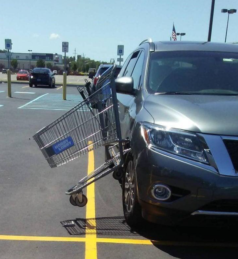 Nákupný vozík zaborený do predného kolesa auta na parkovisku.