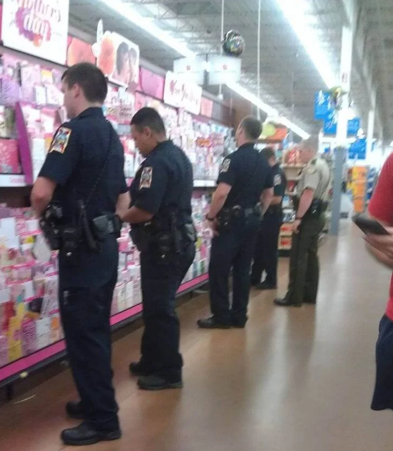 Policajti v obchode so suvenírmi, vyberajú gratulačné karty na deň matiek, veselá nálada v nákupnom centre.