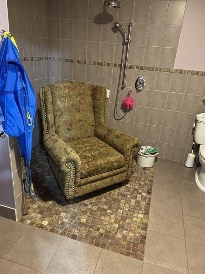 Kreslo v sprchovom kúte kúpeľne vedľa toaletnej misy, neobvyklý dizajn interiéru.