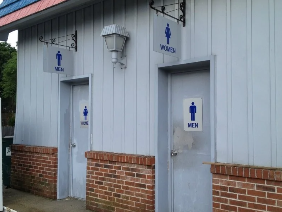 Dvere toalet označené pre mužov a ženy s chybne umiestnenými nápismi na budove.