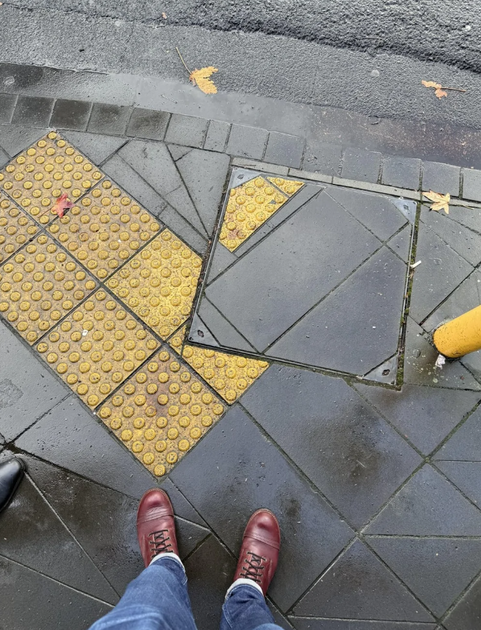 Nesprávne umiestnená dlažba na chodníku vedľa odpadnutého žltého pásu so štruktúrou pre nevidiacich.