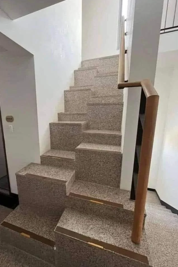 Neštandardné schody s nerovnými stupňami a zábradlím v interiéri domu.