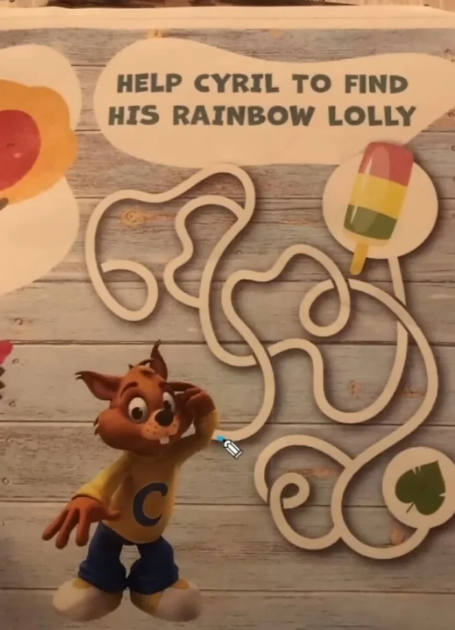 Kreslená postava hľadá cestu bludiskom k dúhovému nanuku na drevenom pozadí.