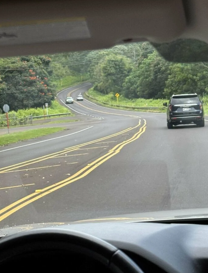 Jazda po kľukatej ceste obklopenej zeleňou, pohľad z interiéru auta na SUV a ďalšie vozidlá.