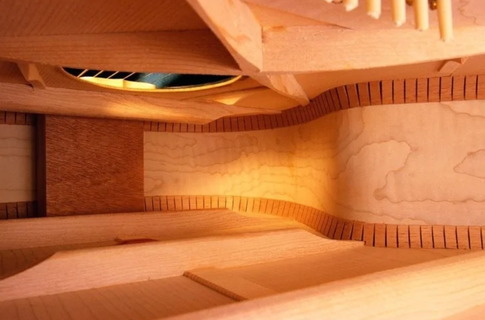 Interiér akustickej gitary so zložito tvarovanými drevenými rebrami a detailom zvukovej dierky.