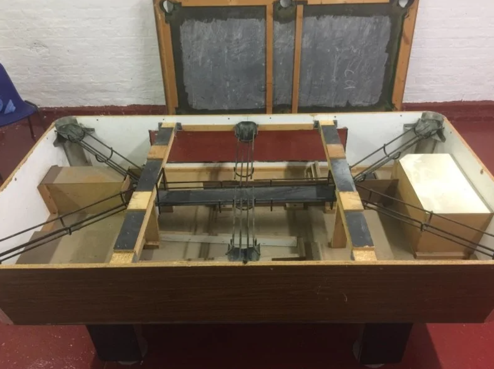 Starý otvorený stôl na stolný futbal, odkryté vnútro s mechanizmami a stierkami.