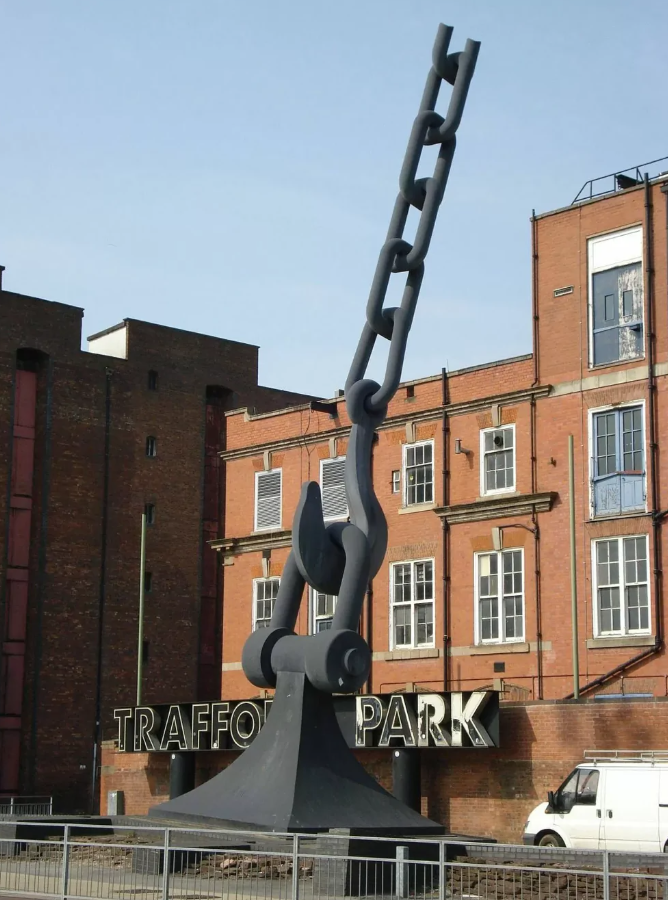 Socha reťaze pred budovou v Trafford Parku na pozadí modrej oblohy, Manchester.
