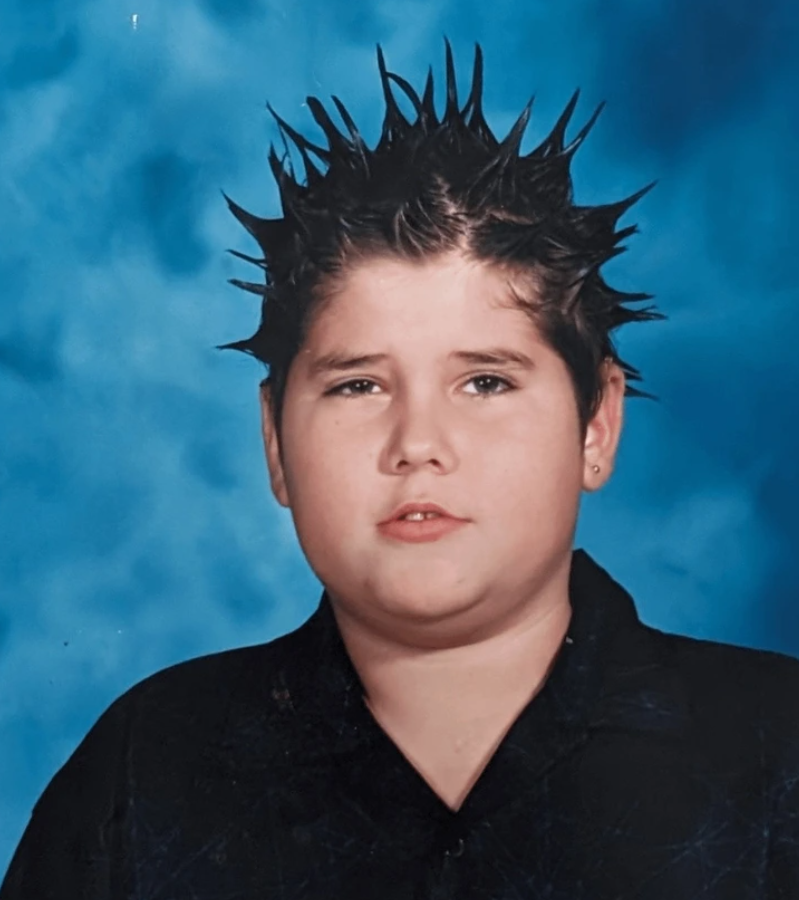 Mladý chlapec s výrazným účesom v štýle ježko na modrom pozadí, portrétová fotografia.