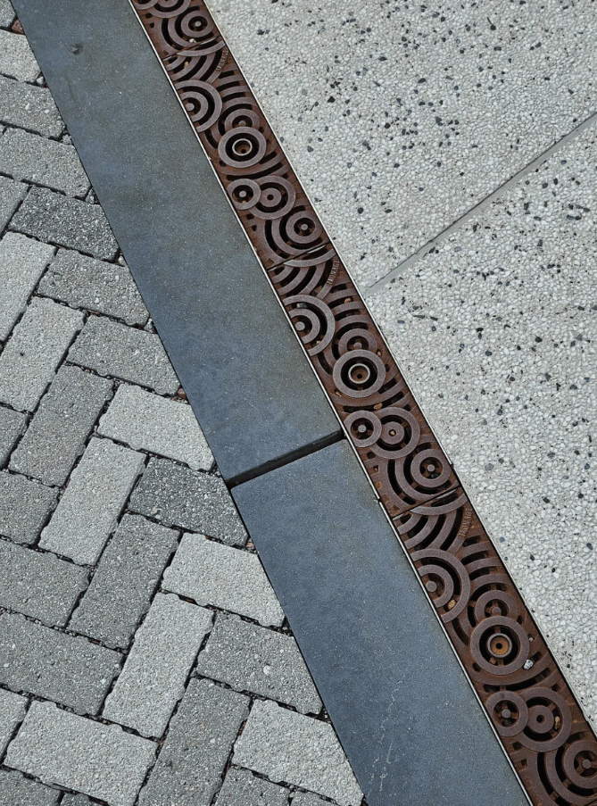 Dekoračný detail kruhového vzoru na odvodňovacom žľabe medzi rôznymi druhmi dlažieb.