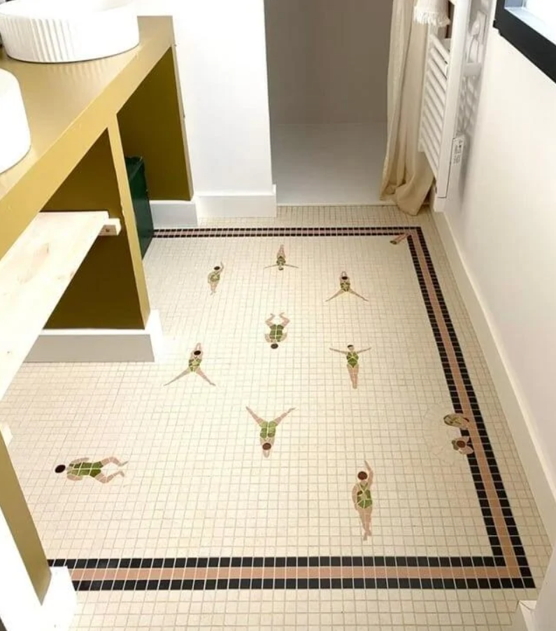 Kreatívna dlažba s motívom plavkýň, v kúpeľni so žltým nábytkom a bielymi umývadlami.