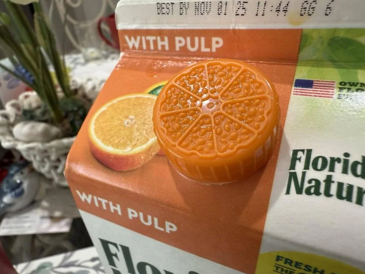 Krabica pomarančového džúsu s vrchnákom napodobňujúcim krúžok pomaranča, označenie: s dužinou.
