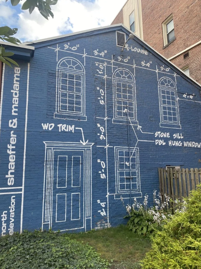 Náčrt architektonických prvkov na modrej stene budovy s presnými rozmermi dverí a okien.