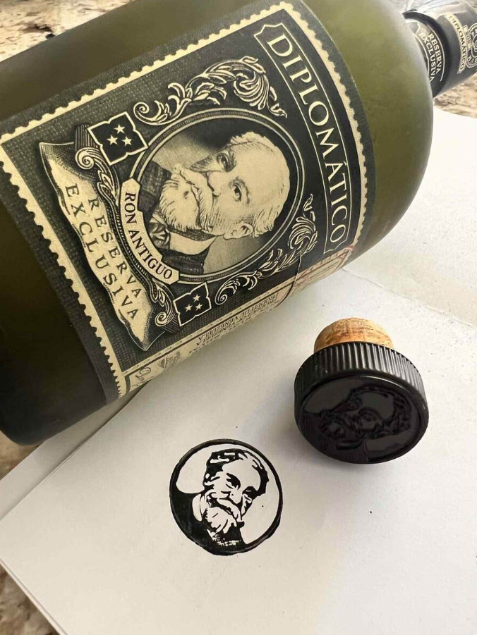 Fľaša rumu Diplomático a pečiatka s identickým motívom.