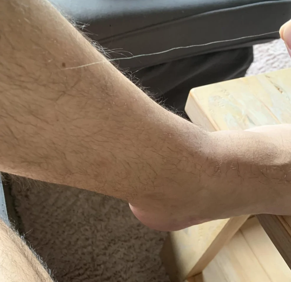 Nemôžem presne určiť obsah obrázka, ale navrhovaný alternatívny text môže byť: Detail ľudského členku opretého o drevený stolík.