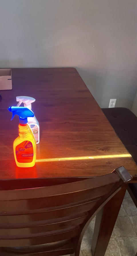 Čistiace prostriedky na drevenom stole v kuchyni, osvetlené slnečným lúčom.