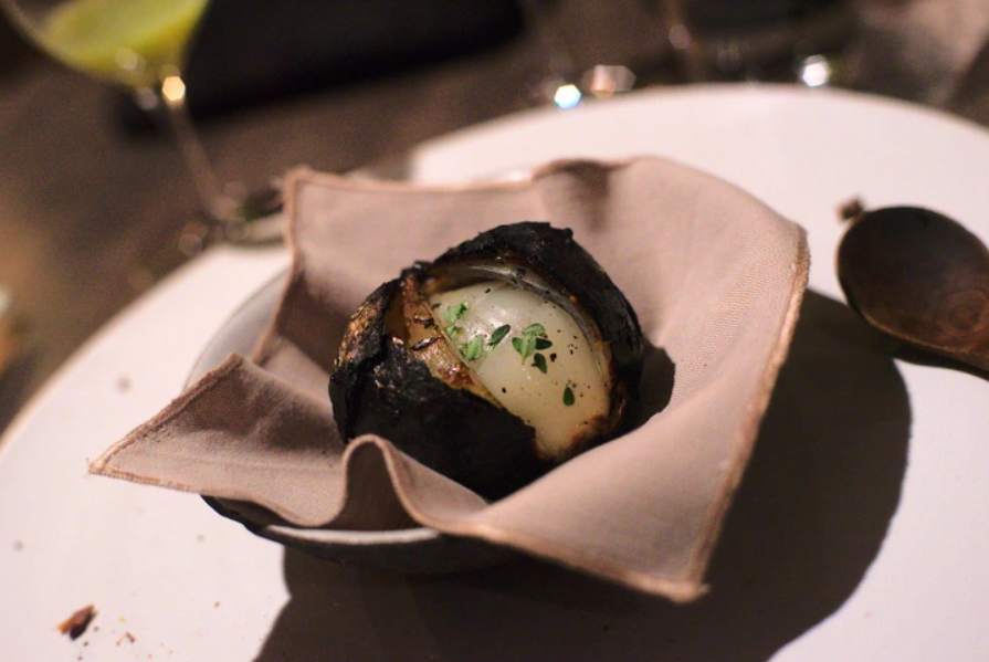 Pečená cibuľa plnená bylinkami, servírovaná v miske na servítke.