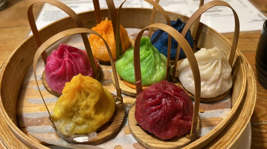 Farebné dim sum knedličky v bambusovom koši, pripravené na podávanie v reštaurácii.