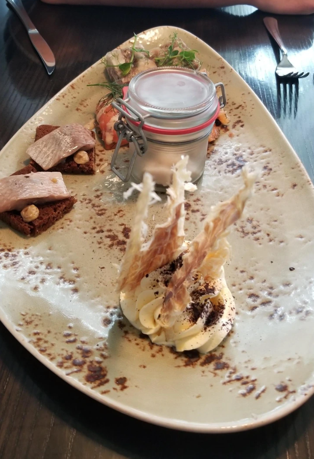 Gurmánsky tanier s rybou, pečivom a krémom na dekoračnom tanieri v reštaurácii.