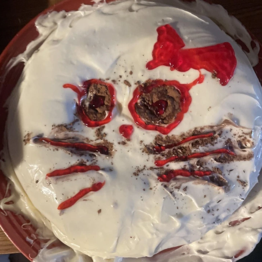Torta so smotanovou polevou a dekoráciou v tvare mačky, červenými očami a mašličkou.