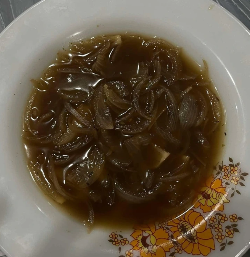 Tanier s cibuľovou polievkou, bohatou na karamelizovanú cibuľu, servírovanou v kvetinovom porcelánovom riade.