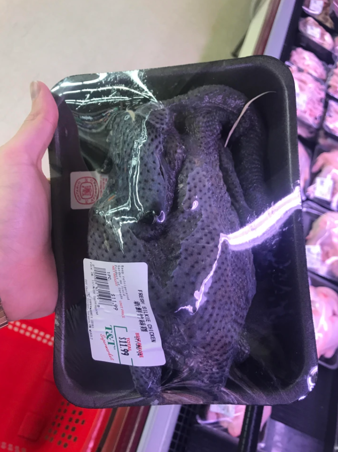 Balené čierne kura v supermarkete, cena a detaily na etikete, chladiaci pult v pozadí.