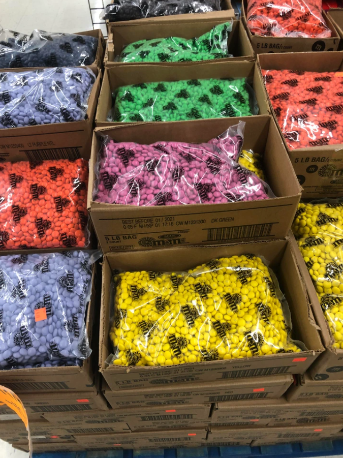 Krabice plné viacfarebných sladkostí zabalených v plastových vreckách na sklade.