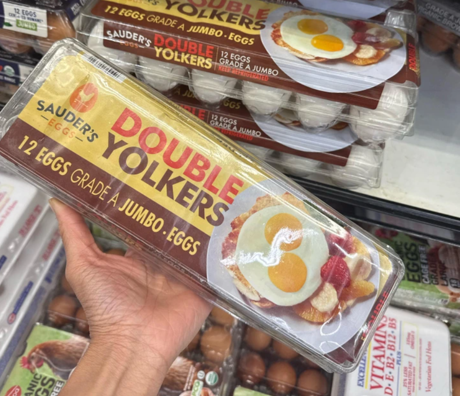 Balenie 12 veľkých vajec s dvomi žĺtkami v supermarkete, držiak v ruke.