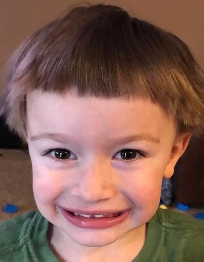 Usmievajúce sa dieťa s ofinou a krátkym účesom v interiéri.