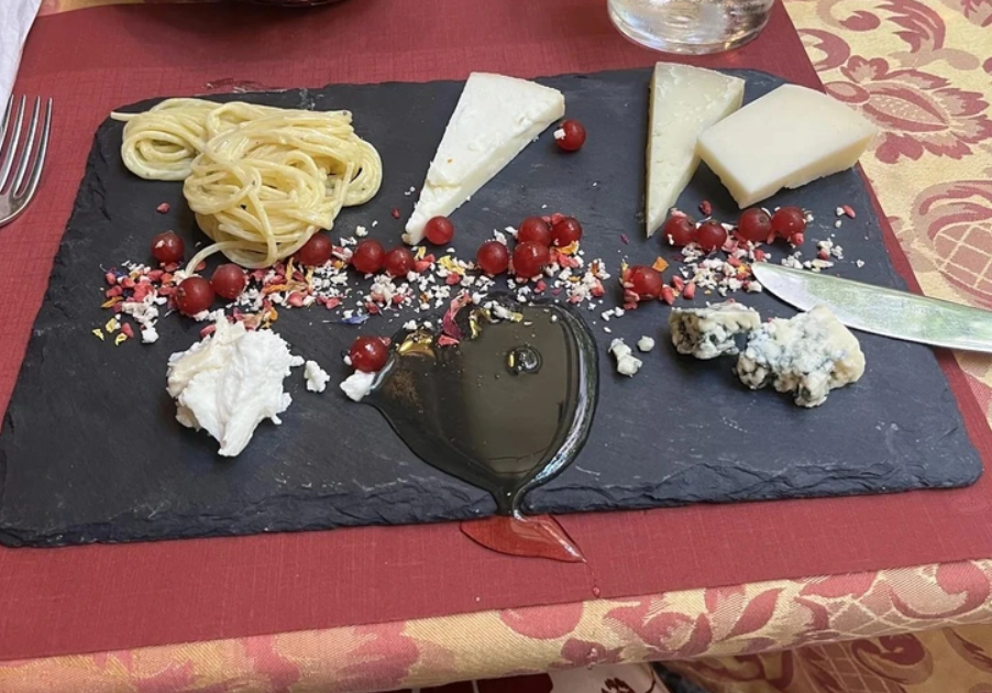 Syrová doska s rôznymi syrmi, orechmi a čučoriedkami na bridlicovej doske.