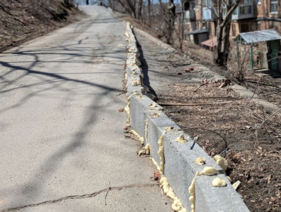 Cesta lemovaná obrubníkom so škárami vyplnenými expandujúcou penou v mestskom prostredí.