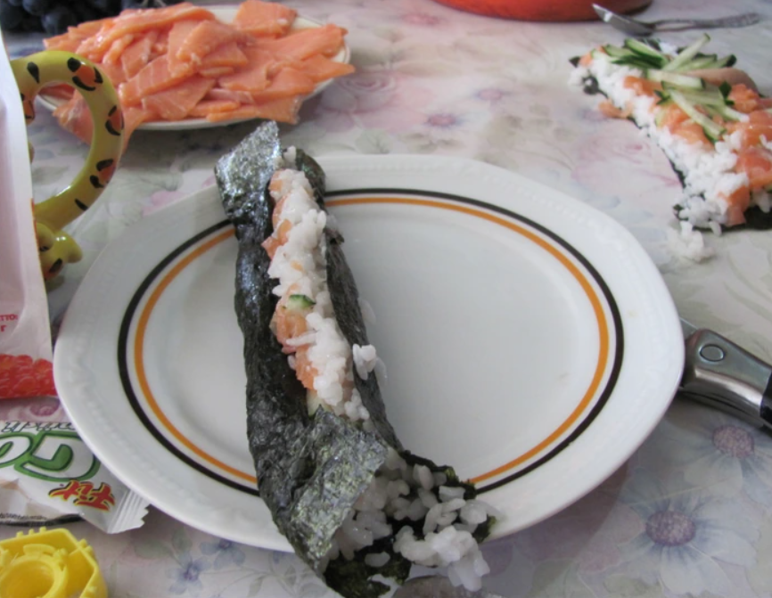 Domáce sushi na tanieri: kus riasy plnený ryžou a lososom, pripravené na servírovanie.