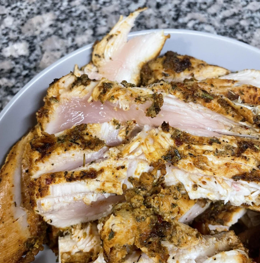 Nesprávne ugrilované kuracie prsia so surovým vnútrom na bielej miske, detailný pohľad.