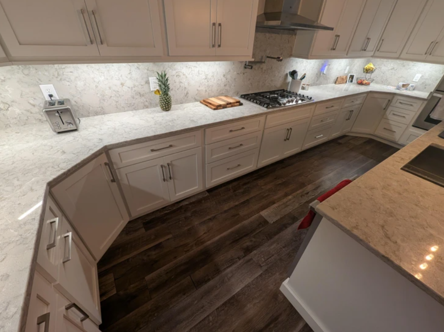 Moderná kuchyňa s bielymi skrinkami a mramorovou pracovnou doskou v drevenom dizajne.