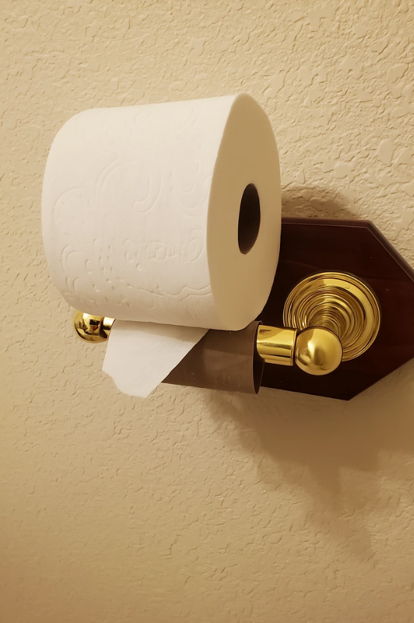 Držiak na toaletný papier s bielym rolkovým papierom na stene kúpeľne.