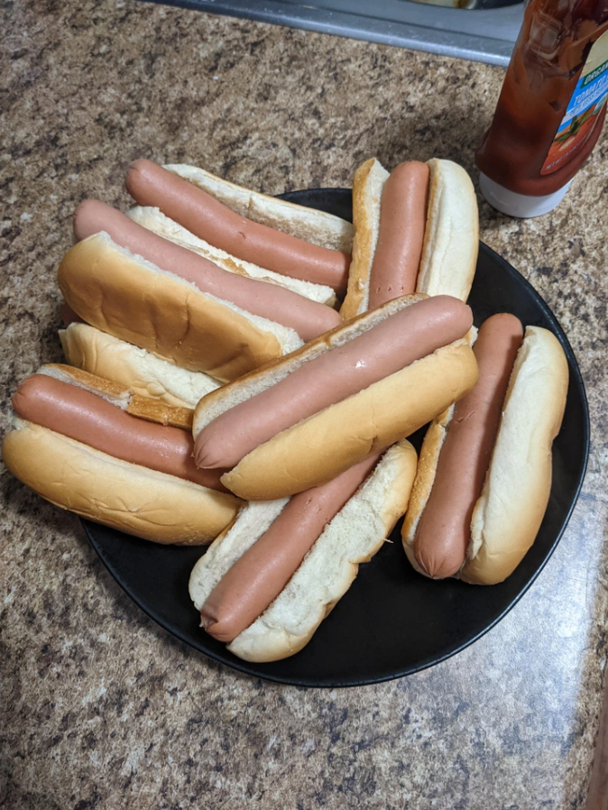 Tanier s klasickými hotdogmi pripravenými na servírovanie na kuchynskej doske.