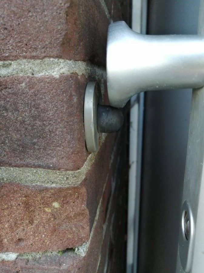 Dverový doraz s gumeným tlmičom na tehlovej stene, zabraňuje poškodeniu steny pri otváraní dverí.