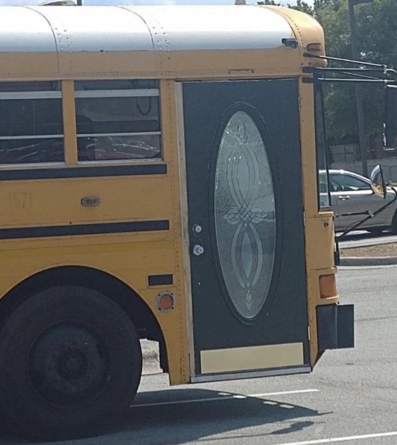 Žltý školský autobus s neobvyklými ozdobnými sklenenými dverami na parkovisku.