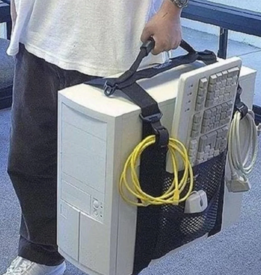 Osoba nesúca starý stolný počítač s klávesnicou a myšou pripevnenými popruhmi.