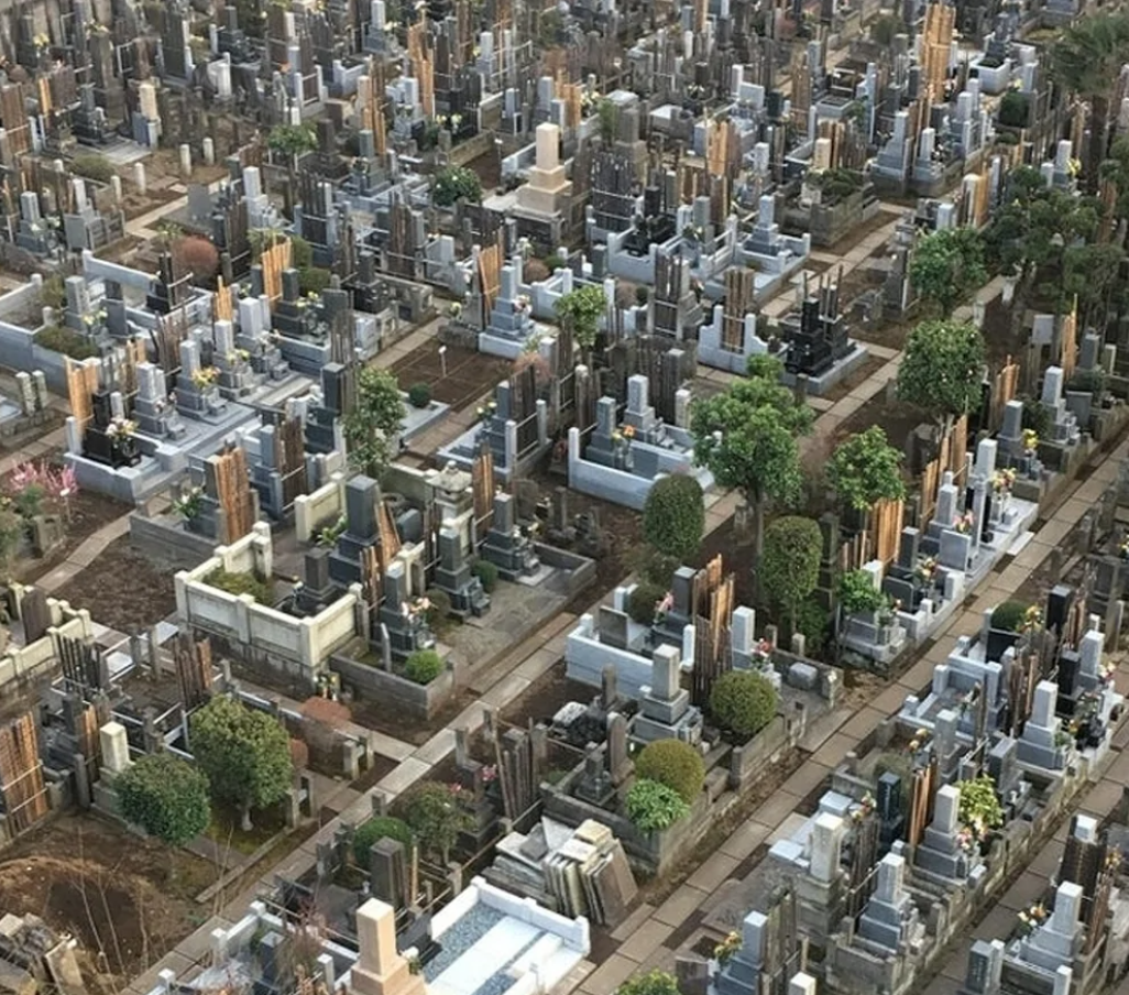 Letecký pohľad na husto osadený cintorín s rôznorodými náhrobkami a zeleňou medzi pomníkmi.