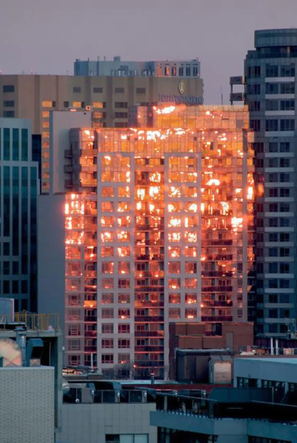 Odrážané svetlo zapadajúceho slnka vytvára dojem horiaceho mrakodrapu v centre mesta.