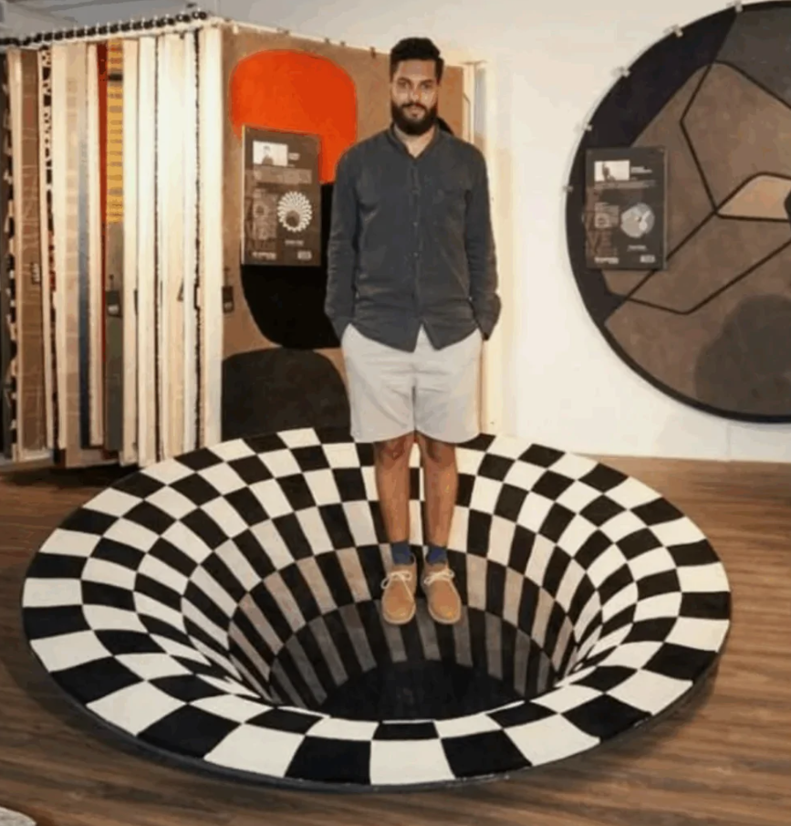 Muž stojí na optickom iluzórnom koberci s čiernobielou šachovnicou vytvárajúcou efekt jamy.