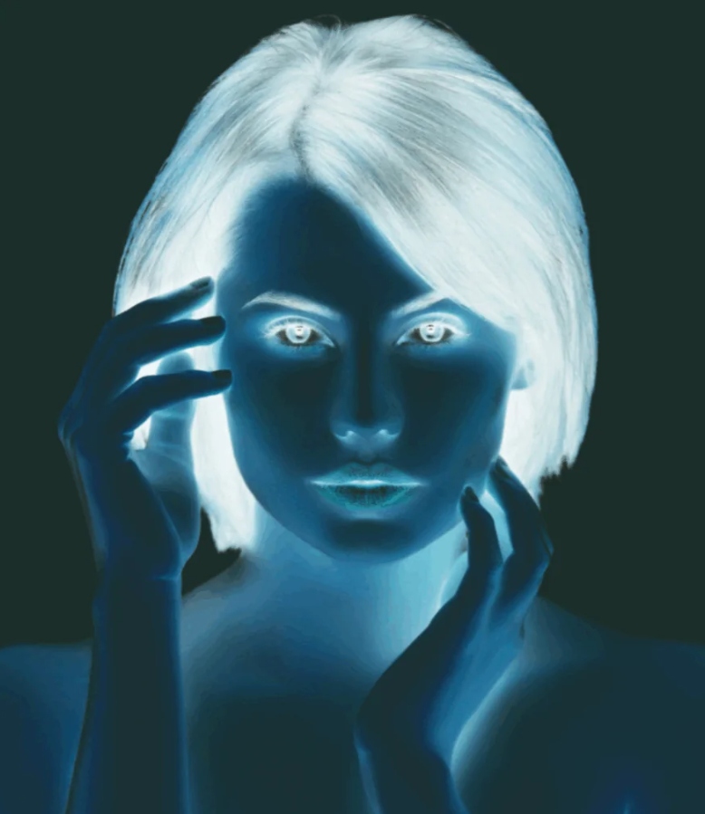 Obrázok osoby v negatívnej expozícii, s výraznými očami a rukami pri tvári, na tmavom pozadí.