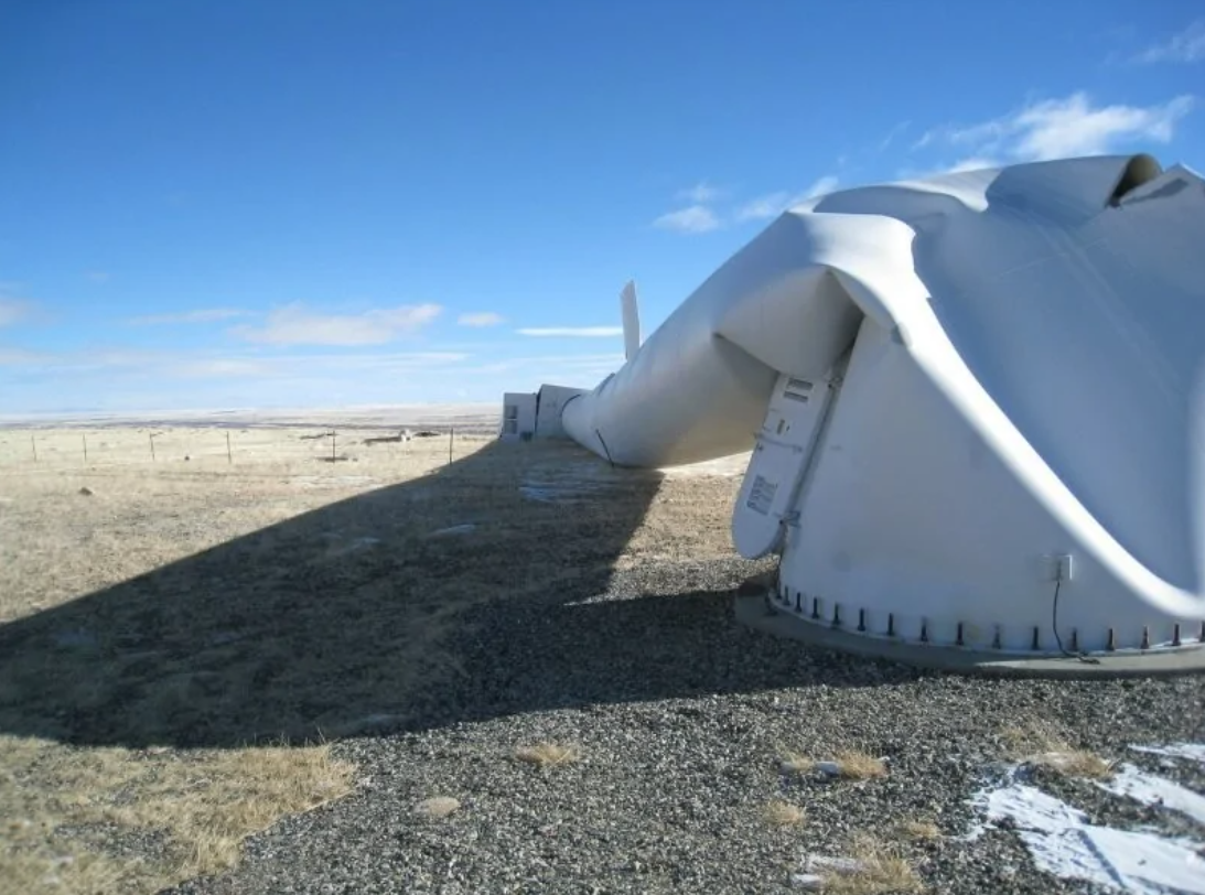 Vyzvalená veterná turbína na otvorenom poli, jasná obloha v pozadí.