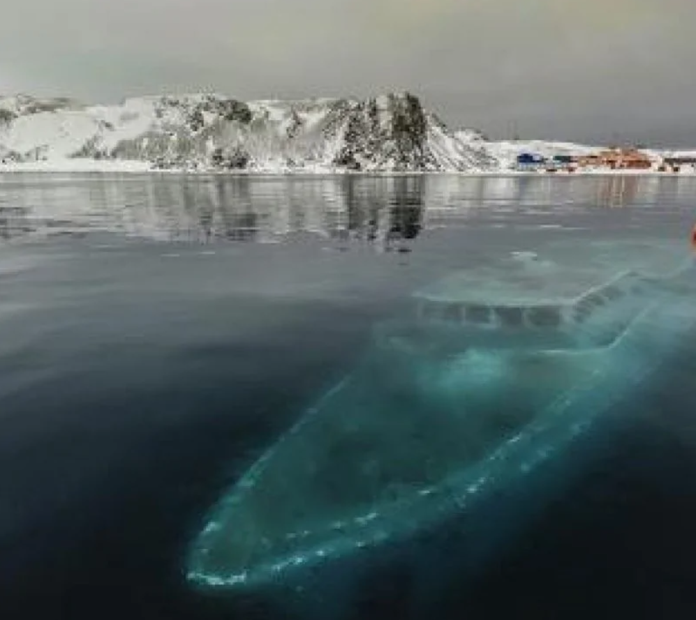 Ľadovec a potopený vrak lode pod hladinou v zamrznutej antarktickej krajine.