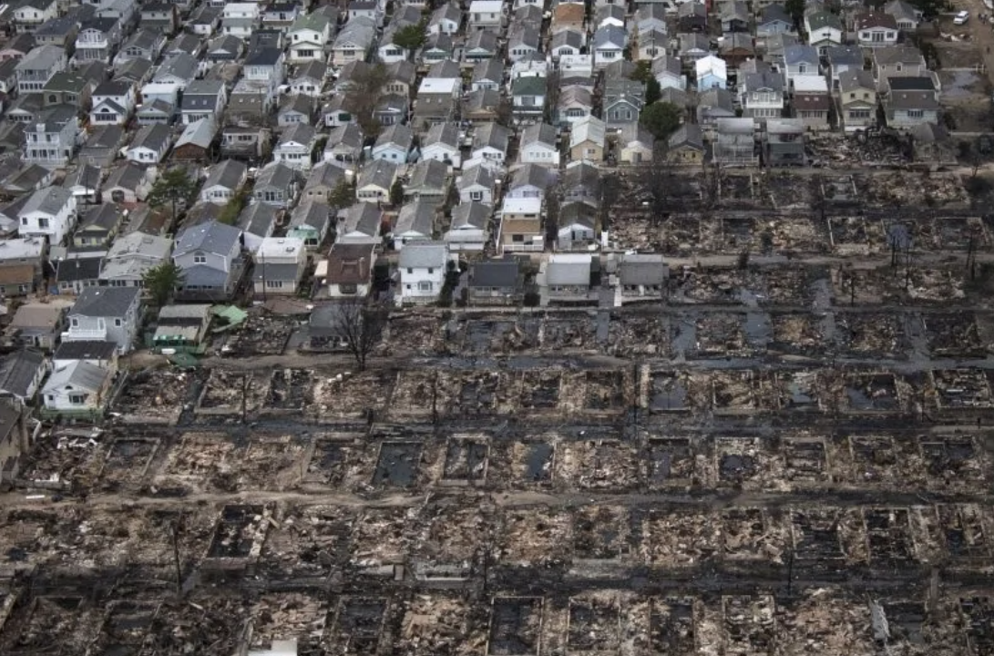 Letecký pohľad na obytnú zónu zničenú požiarom, jasný kontrast medzi nedotknutými a poškodenými domami.