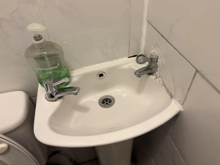 Malé umývadlo v kúpeľni s mydlovou pumpičkou na okraji a pokazenou vodovodnou batériou.